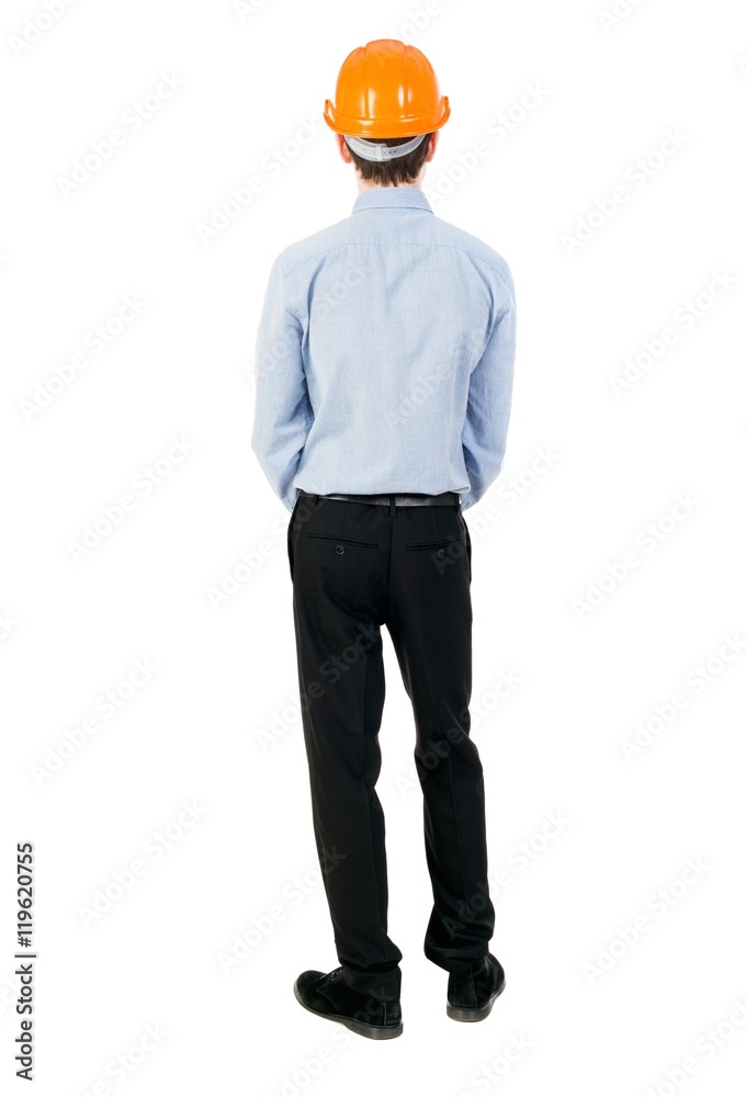 Backview of an engineer in construction helmet stands. Isolated over white background. The curly-haired businessman in light shirt and hat thoughtfully looks ahead. Backview of an engineer in construction helmet stands. Isolated over white background. The curly-haired businessman in light shirt and hat thoughtfully looks ahead.