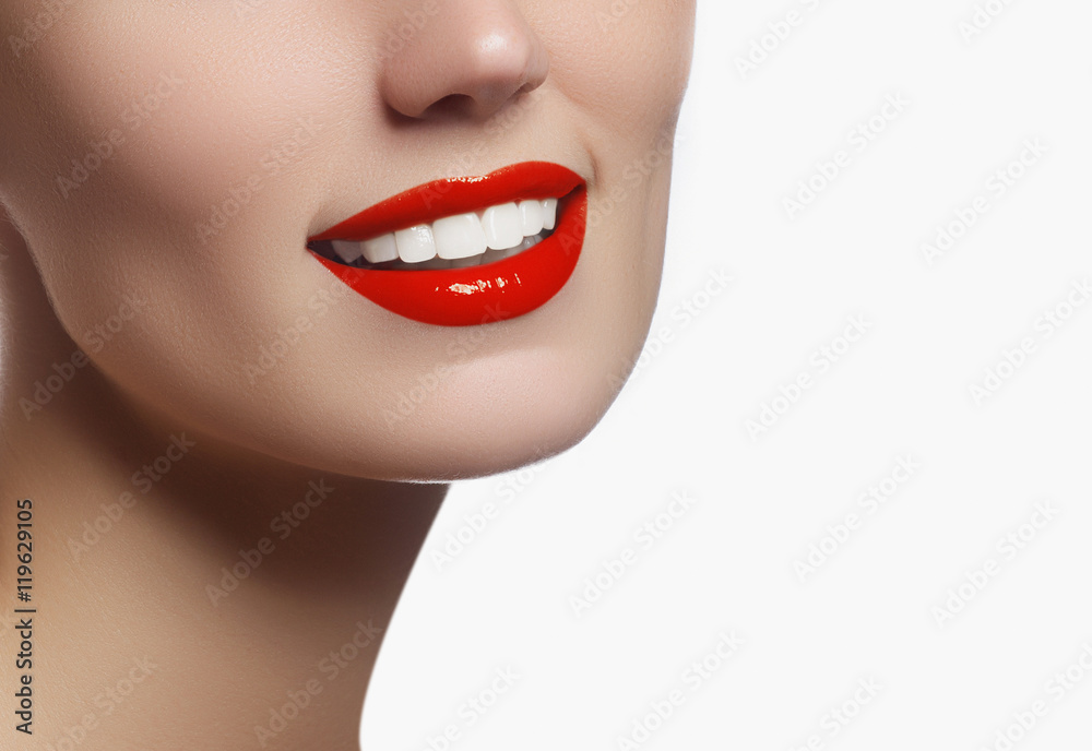 Obraz premium Perfect smile with white healthy teeth and red lips, dental care concept. Beautiful young woman's face fragment with natural smile. Woman smile, teeth whitening, dental care.