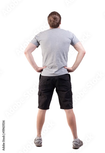 Back view of handsome man in t-shirt and shorts looking up. Standing young tourist. Rear view people collection. backside view of person. Isolated over white background. her hands on her hips