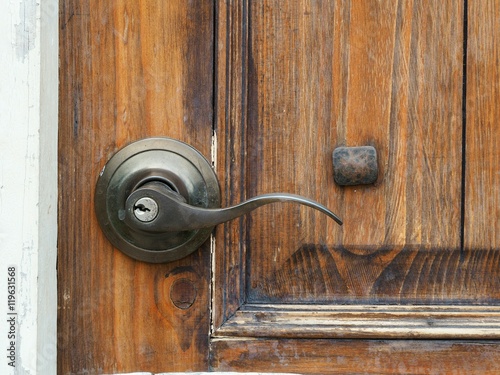 The old metal door handle on the wooden door