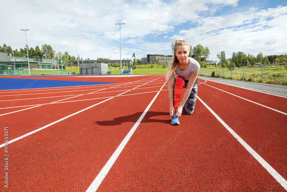 Fototapeta premium Confident Woman Tying Shoelace On Running Tracks