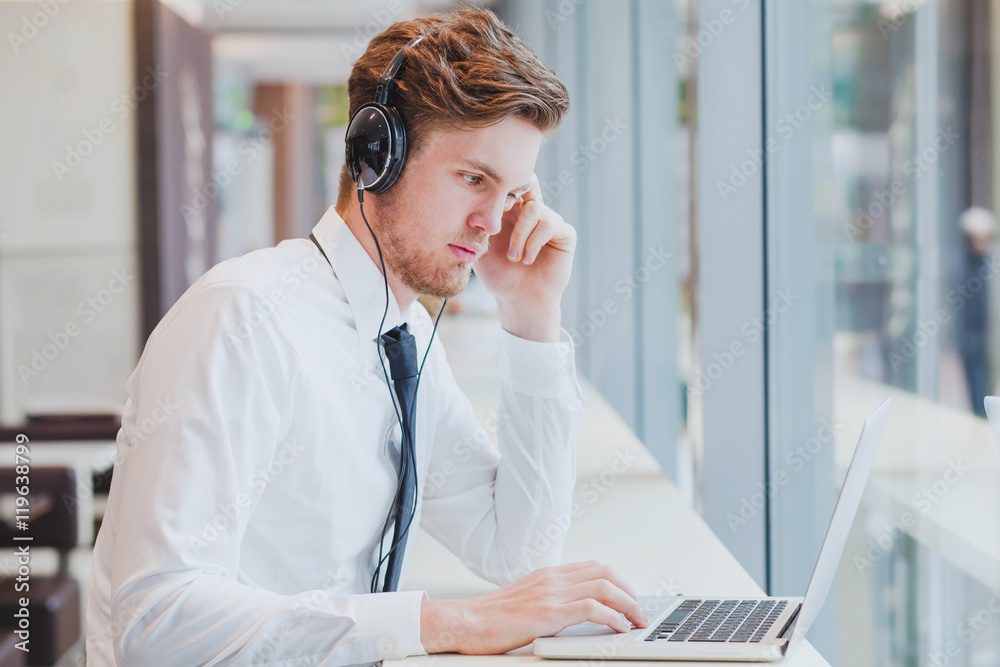 businessman in headphones working with laptop in modern cafe interior businessman in headphones working with laptop in modern cafe interior