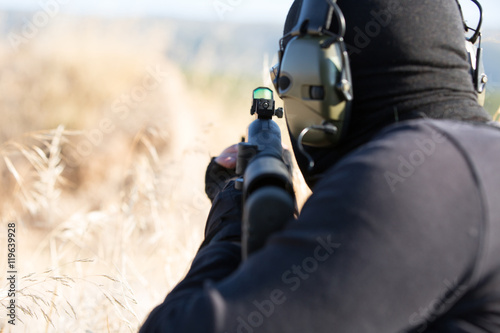 Man with rifle aiming in grassy field