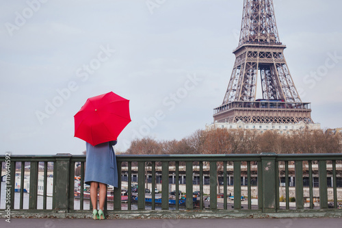 Photography woman with red umbrella standing on the bridge with the view of Eiffel tower in
