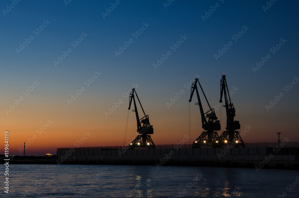 PORT CRANES AT NIGHT. Cruise Ship Terminal in Gdynia. Outline of port cranes at dawn. 