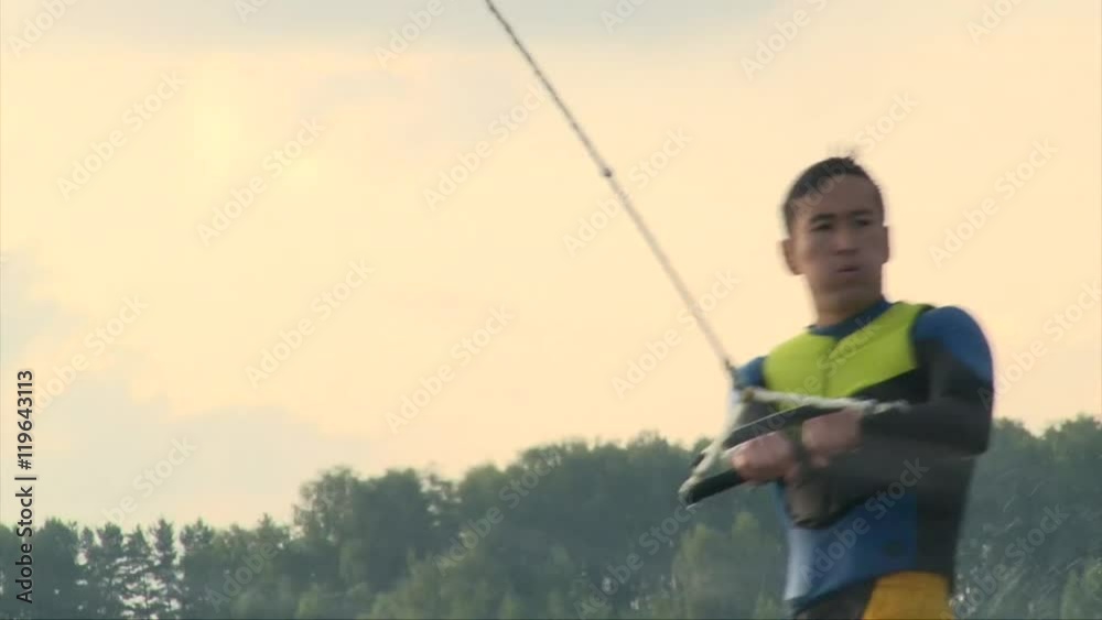 Close up shot of wakeboarder man in diving suit riding the wave and crush in water, summer sunset on the lake Close up shot of wakeboarder man in diving suit riding the wave and crush in water, summer sunset on the lake