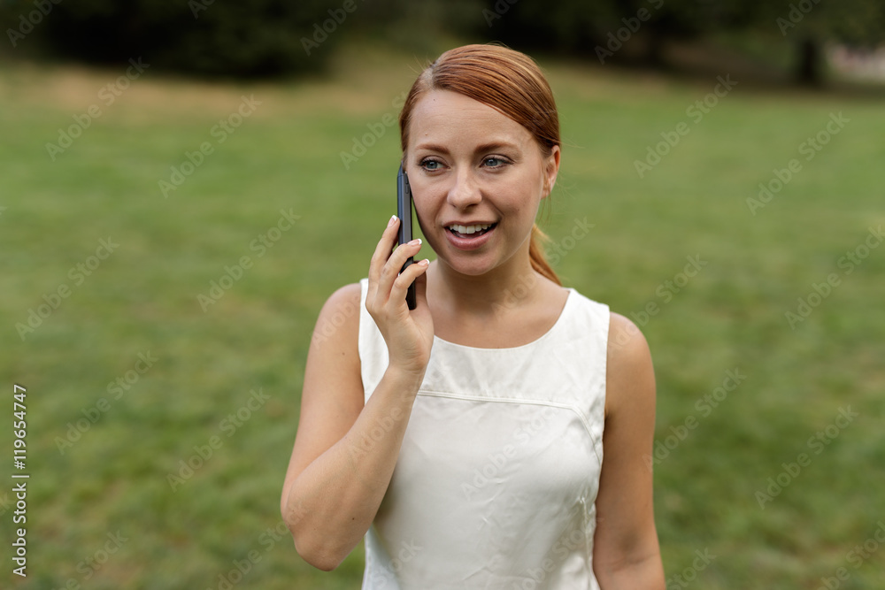 Caucasian woman in city park talking on cell phone Caucasian woman in city park talking on cell phone