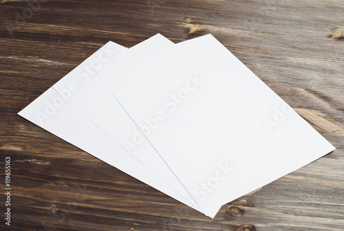 
three white papers on a wooden background, mock up