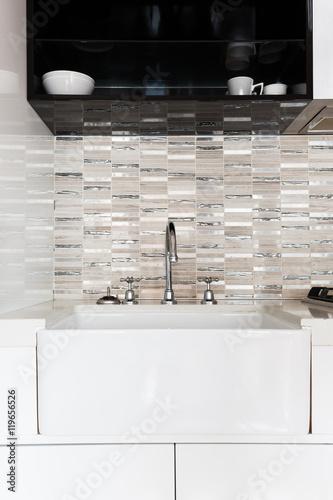 Close up of a deep white kitchen sink and tiled splashback photo