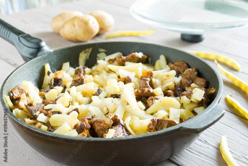 fried potatoes with mushrooms in a frying pan fried potatoes with mushrooms in a frying pan