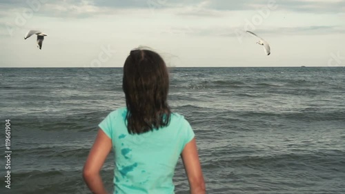 Girl feeds seagulls on the seacoast photo