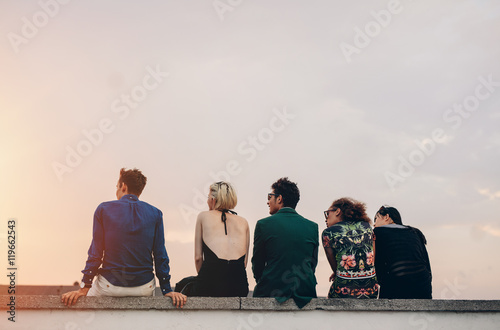 Young people hanging out on rooftop at sunset