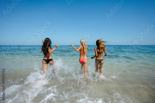 Three beautiful young women running in the sea