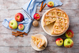 Homemade pie with apples, cinnamon and cream on white rustic wooden background, top view