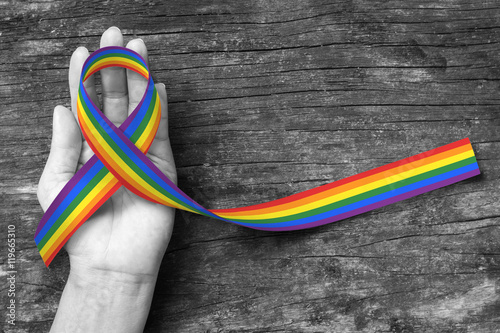 Rainbow color ribbon awareness on human hand on BNW background, clipping path: Symbolic color logo icon for equal rights in love and marriage social equality of LGBT community/ people concept photo