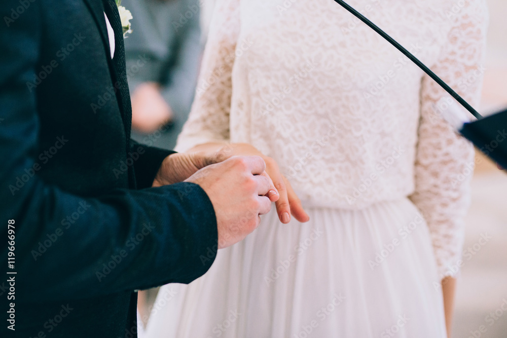 Groom putting a ring on bride's finger during wedding ceremony Groom putting a ring on bride's finger during wedding ceremony