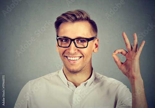 man gesturing OK sign isolated on gray wall background