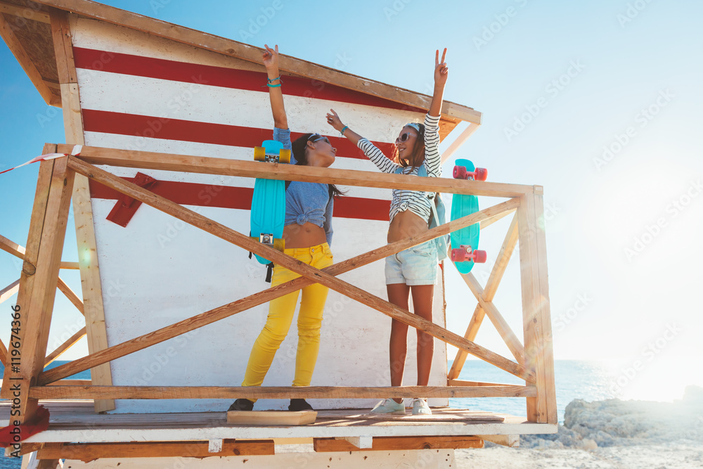 Two 10 years old children wearing cool clothing posing with colorful skateboards on the beach, urban style, pre teen summer fashion.