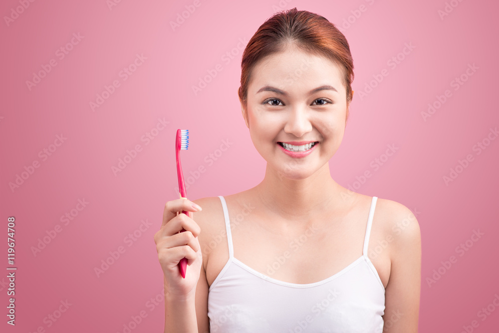 Smiling young woman with healthy teeth holding a tooth brush ove Smiling young woman with healthy teeth holding a tooth brush ove