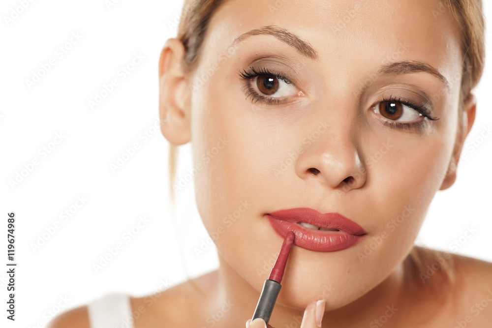 young beautiful woman outlining her lips with a pencil young beautiful woman outlining her lips with a pencil