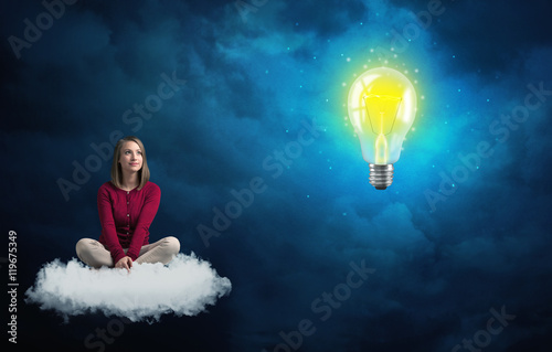 Woman sitting on a cloud lokking at huge lightbulb