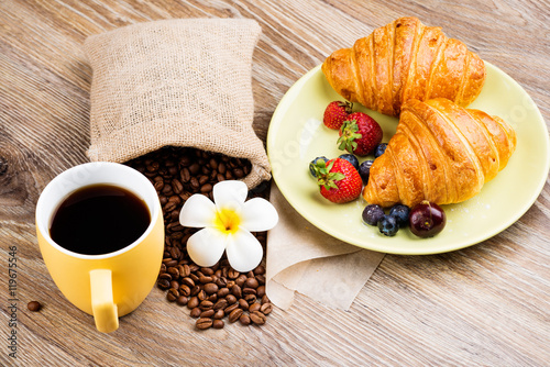 Cup of coffee and croissants on wooden background