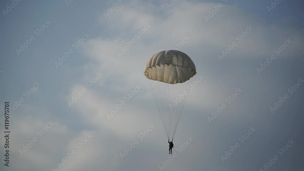 paratrooper landed on the grass and blue sky with clouds, white parachute paratrooper landed on the grass and blue sky with clouds, white parachute