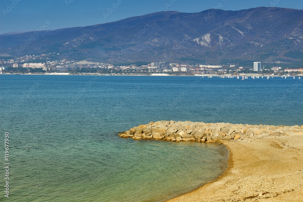 Sea resort town of Gelendzhik in sunny day on Black sea coast. View on sandy beach and city center with mountains in background