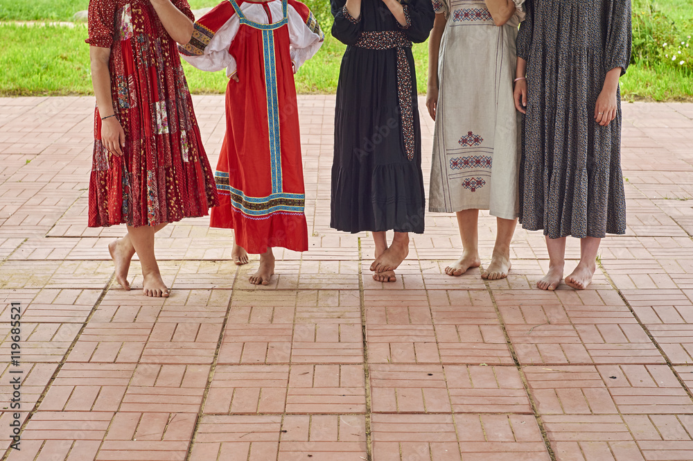 Barefoot girls in folk dresses on the concert of folk music outdoors 