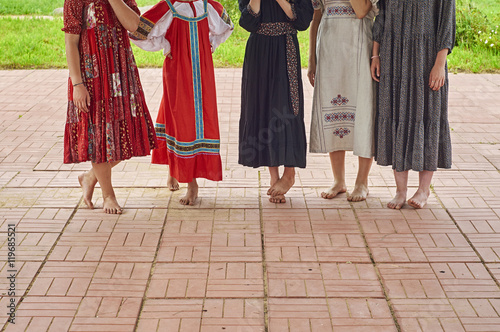 Barefoot girls in folk dresses on the concert of folk music outdoors 