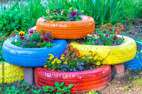 Old tires that are painted in assorted colors and used for a flower planter. photo
