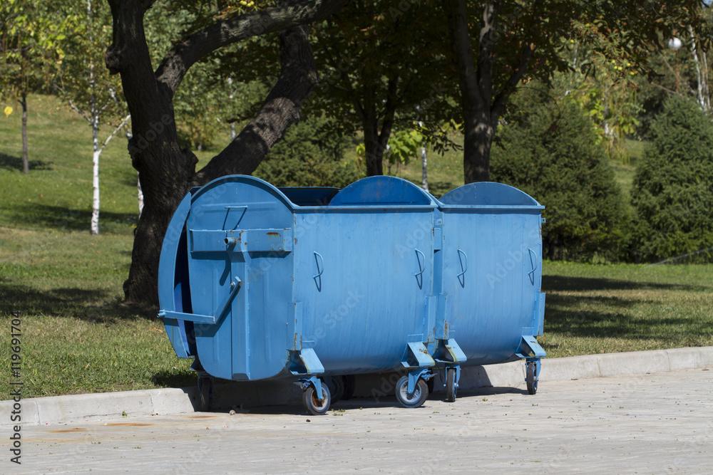 Two blue garbage containers at park Two blue garbage containers at park