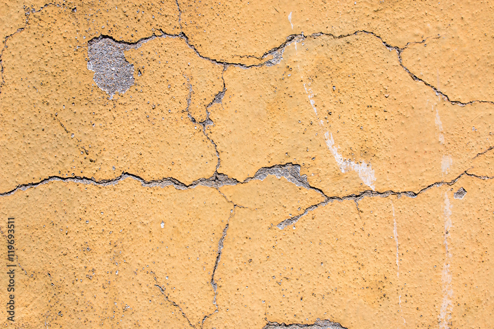 Fototapeta premium Hintergrund gelbe verputzte Mauer mit Rissen