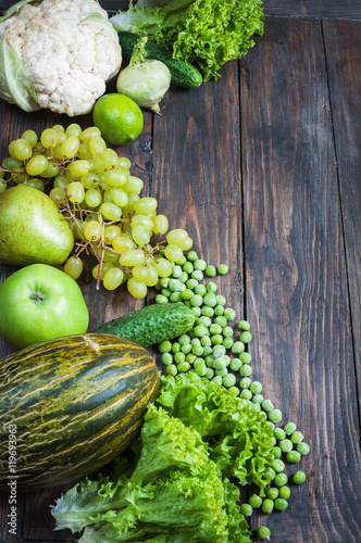 green vegetables and fruits on dark wooden background.