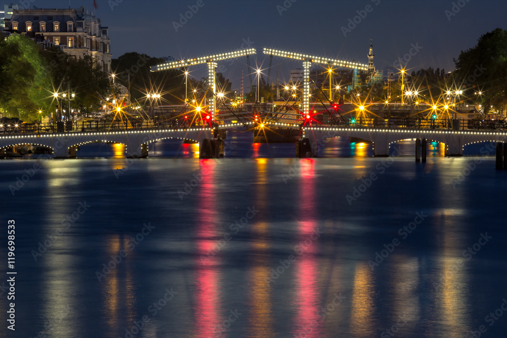 Magere Brug, Skinny bridge, with night lighting over the river Amstel in the city centre of Amsterdam, Holland, Netherlands