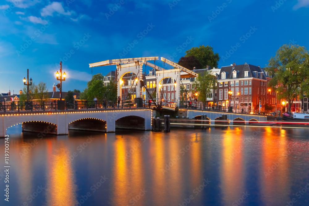 Naklejka premium Magere Brug, Skinny bridge, with night lighting over the river Amstel in the city centre of Amsterdam, Holland, Netherlands