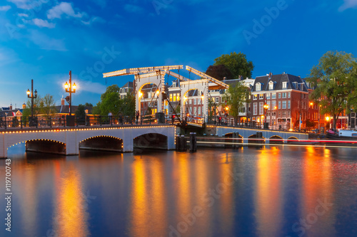 Magere Brug, Skinny bridge, with night lighting over the river Amstel in the city centre of Amsterdam, Holland, Netherlands