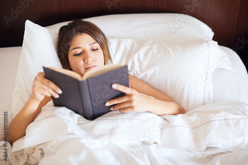 Woman reading a book in her bed