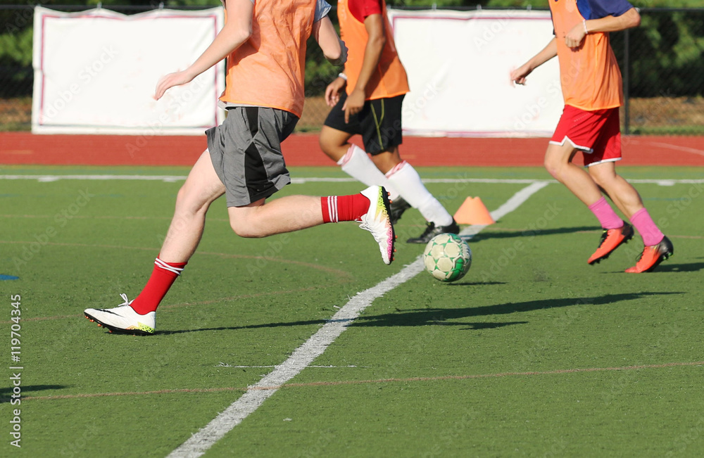 three soccer players bring the ball down the field at practice