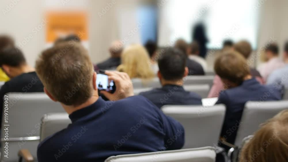 Business presentation on projective screen on a conference and listeners back Business presentation on projective screen on a conference and listeners back