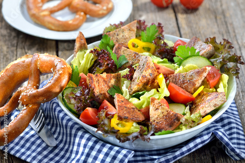 Bayerische Salatschüssel: Gebratene Milzwurst auf buntem Salat mit Breze serviert - Bavarian salad: Fried sausage with pieces of spleen served on a colorful salad photo