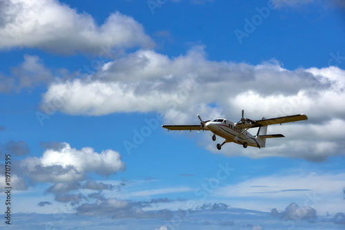 Small passenger propeller plane flying in blue cloudy sky 