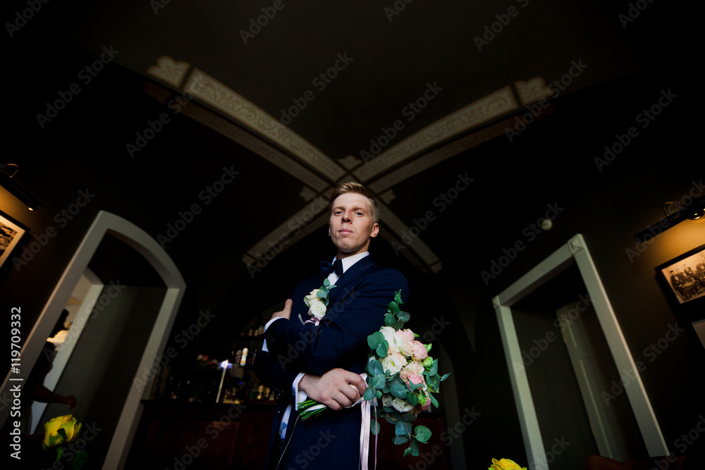 Fototapeta premium Handsome groom standing with amazing bouquet