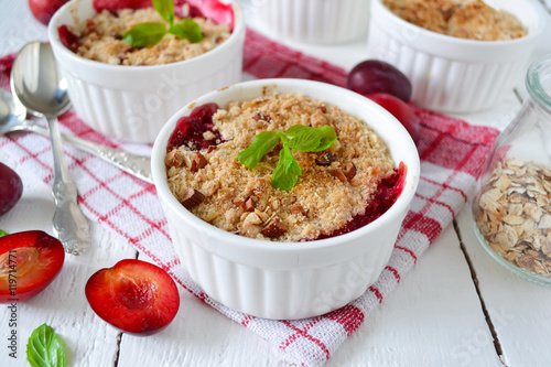 Oat crumble with plums, spices and honey on a light background