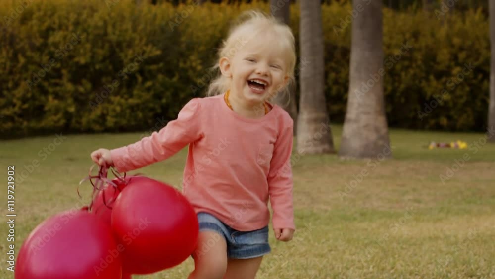 Little girl running to camera with red balloons in park Little girl running to camera with red balloons in park