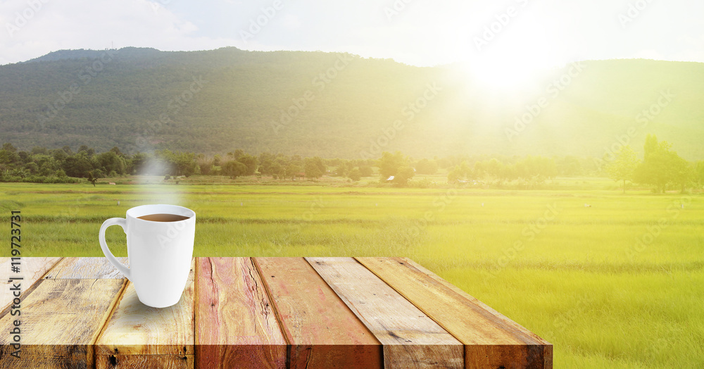 Close up white coffee cup on wood table and view of sunset or sunrise background