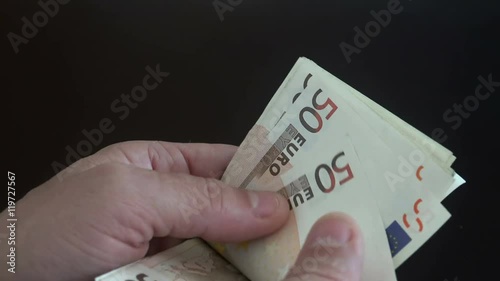 Close-up of a businessman’s hands counting euro bills at a table photo