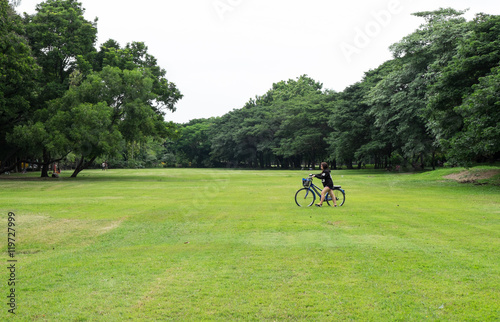 A women with her bicycle in a beautiful park