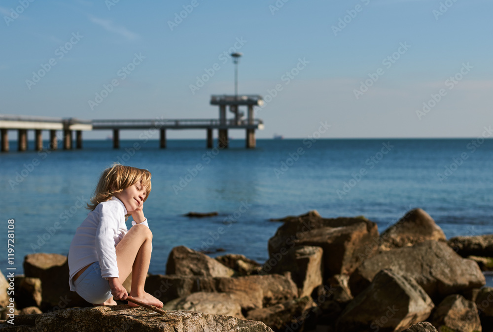 Young boy on sea beach rocks