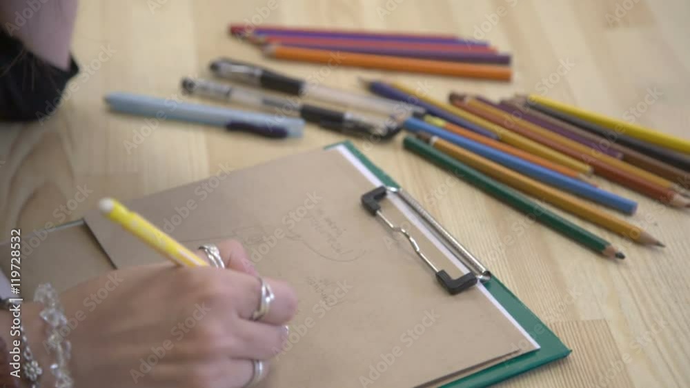 It is close-up image of artist hand, workplace with lots of colorful pencils It is close-up image of artist hand, workplace with lots of colorful pencils